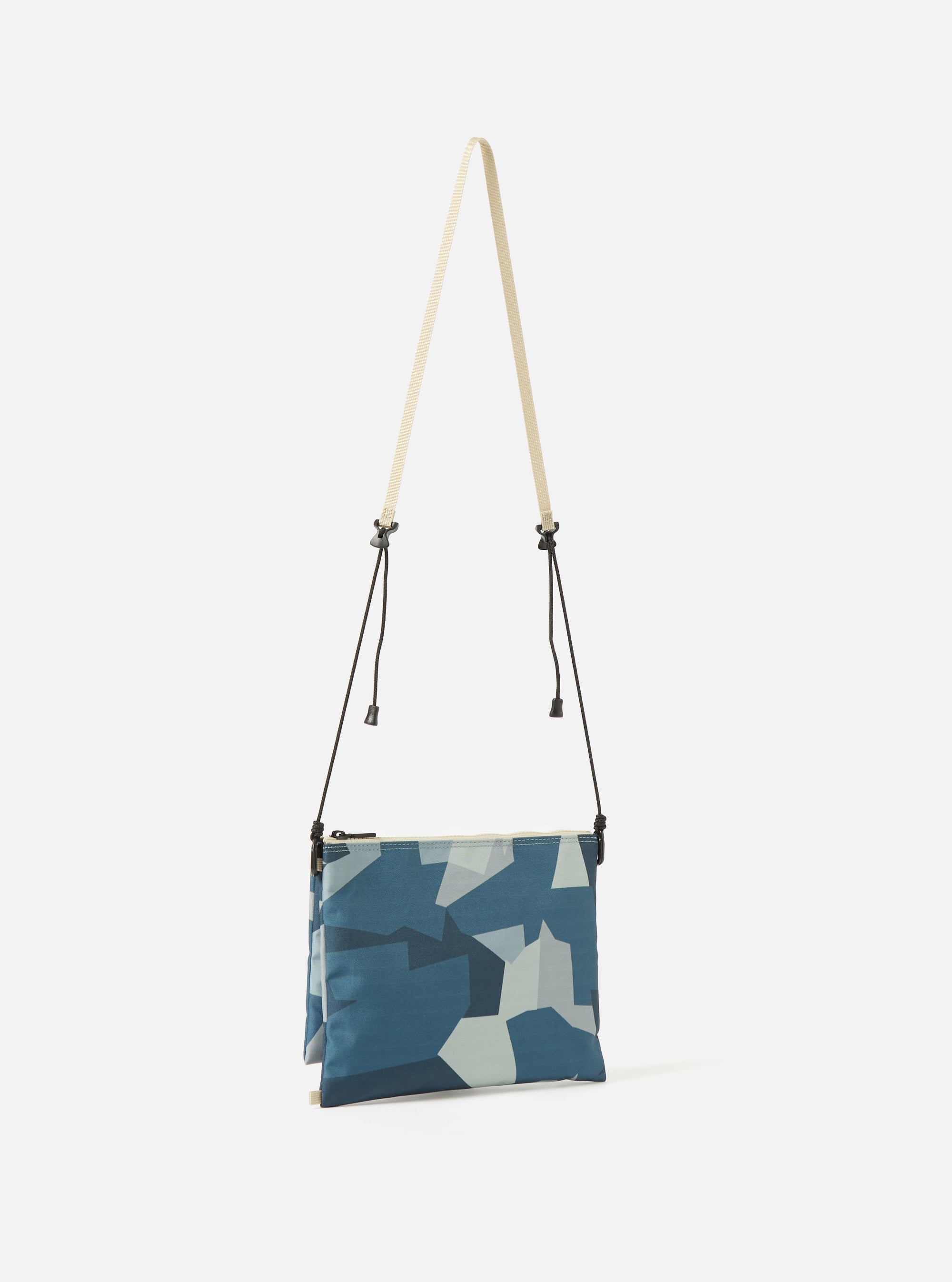 master-piece x Universal Works Blue Camo Recycled Tech Canvas Sacoche bag in blue camo print, hanging against a white background with a beige strap and black drawstrings.