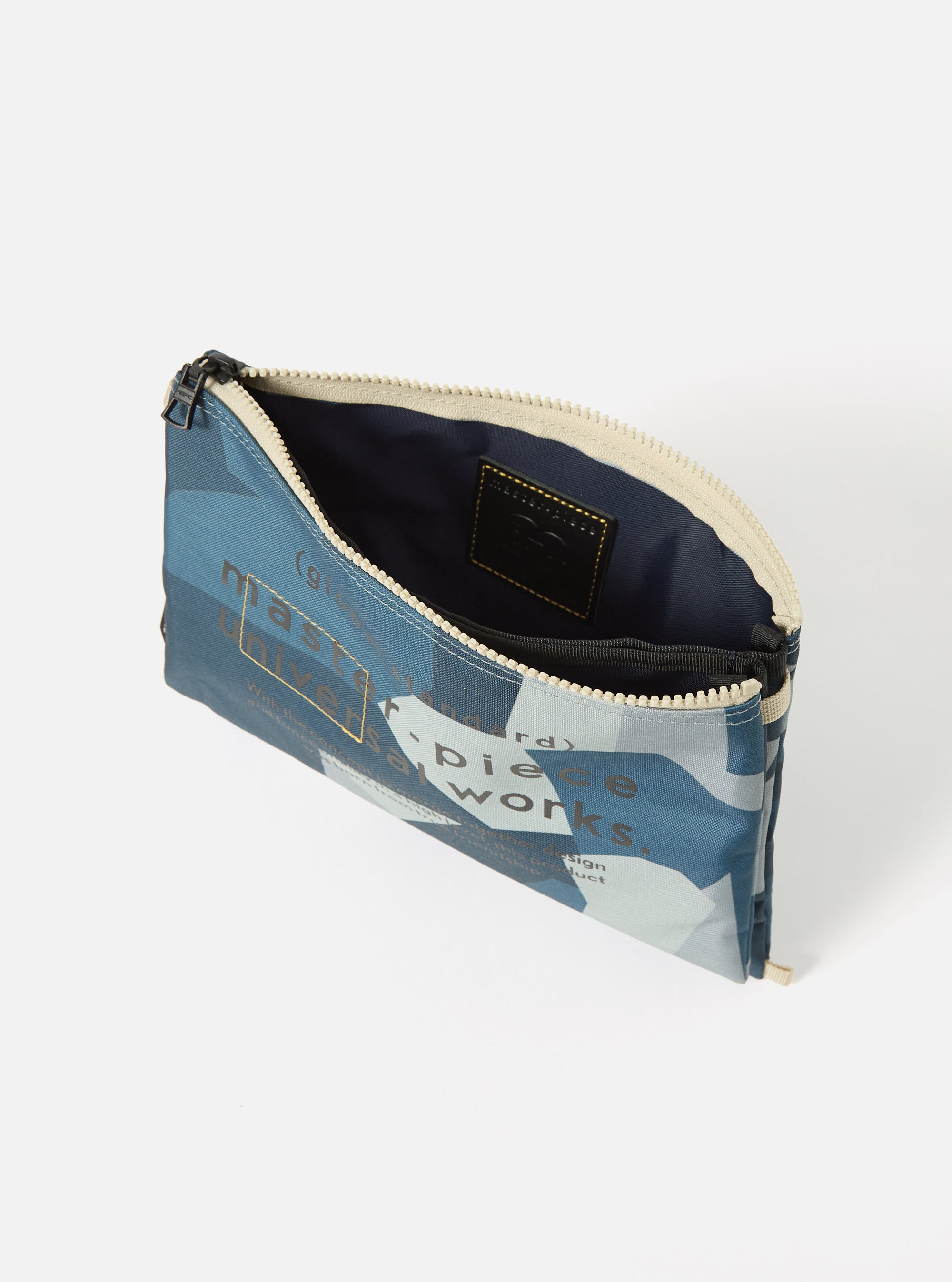 Open master-piece x Universal Works Blue Camo Recycled Tech Canvas Sacoche on a white background. The bag has a blue camo pattern and a beige zipper.