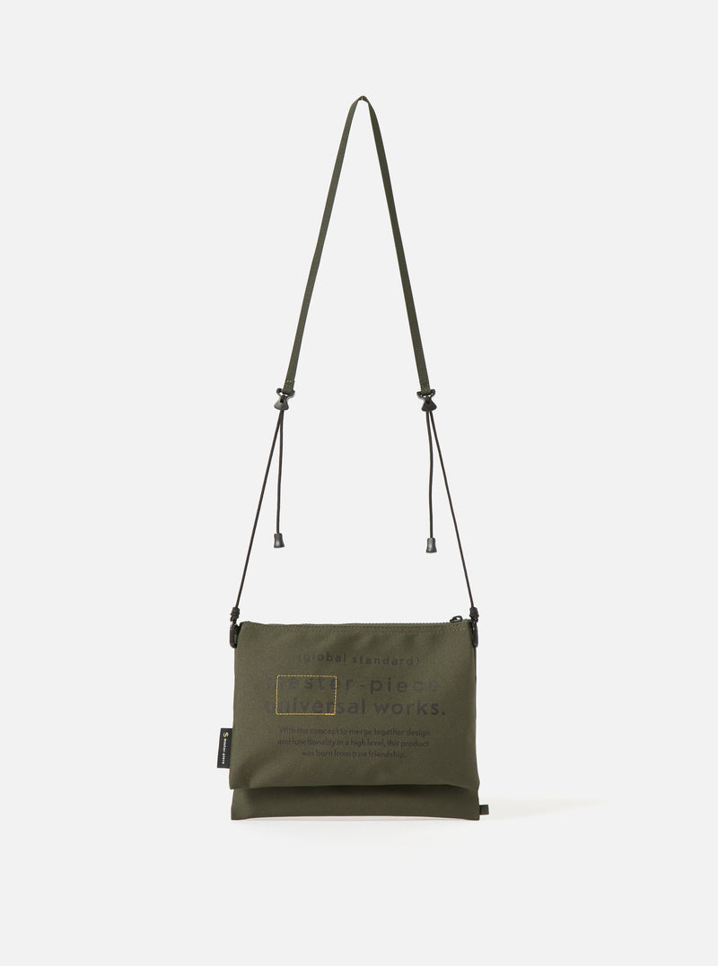 master-piece x Universal Works Olive Recycled Tech Canvas Sacoche on a clean white background. The olive green bag features black drawstrings and subtle branding.