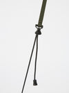 Close up of the olive strap and black drawstrings of the master-piece x Universal Works Olive Recycled Tech Canvas Sacoche against a white background.