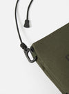 Close-up of the master-piece x Universal Works Olive Recycled Tech Canvas Sacoche on a white background. Shows the olive canvas material, black strap, and hardware details.