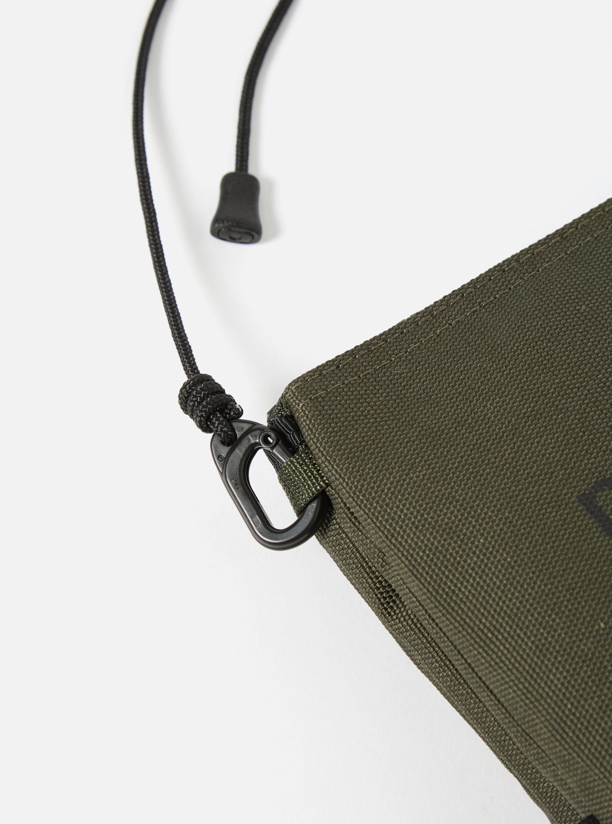 Close-up of the master-piece x Universal Works Olive Recycled Tech Canvas Sacoche on a white background. Shows the olive canvas material, black strap, and hardware details.