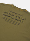 The master-piece x Universal Works Olive Single Jersey Print Tee is shown as a flat lay against a white background. The image displays a close-up detail of the garment, focusing on the back neck area and the internal branding labels. A blue master-piece brand tag is visible next to a white Universal Works label. The olive green cotton jersey fabric is prominent.