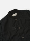 The master-piece x Universal Works Black Peached Poplin Newark Jacket is shown as a flat lay against a plain white background. The jacket features a rounded collar, a central button-down front, and two large patch pockets at the waist. The black peached poplin fabric has a smooth, matte finish.