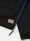 The master-piece x Universal Works Black Peached Poplin Newark Jacket is shown from a rear three-quarter angle as a flat lay against a plain white background. The image highlights the smooth black cotton fabric, the ribbed collar and cuffs, and a small collaborative brand patch near the hem.