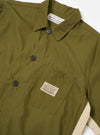 The master-piece x Universal Works Olive Recycled Poly Tech Tech Overshirt is shown from a rear three-quarter angle as a flat lay against a plain white background. The image highlights the back yoke with a central box pleat and the short sleeves of the garment. The olive green recycled polytech fabric has a smooth, technical appearance.