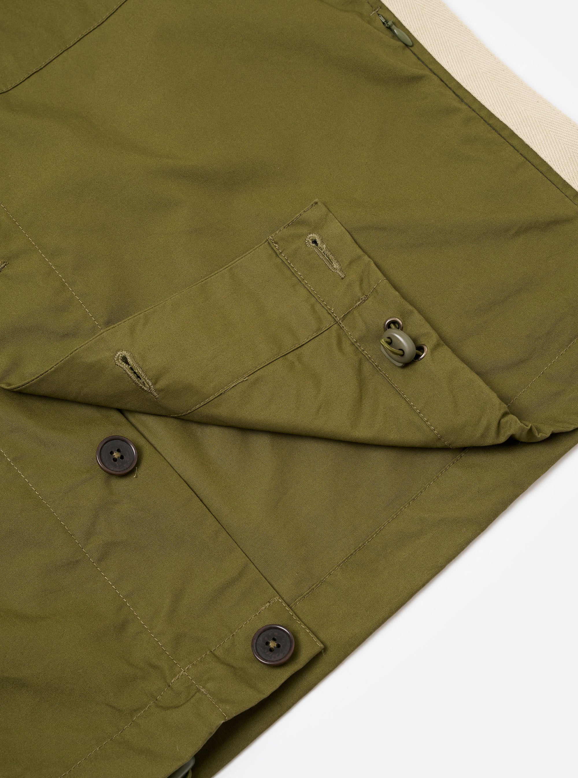 The master-piece x Universal Works Olive Recycled Poly Tech Tech Overshirt is shown from the back as a flat lay against a plain white background. The image highlights the back yoke with a central box pleat and the smooth, olive green recycled polytech fabric.