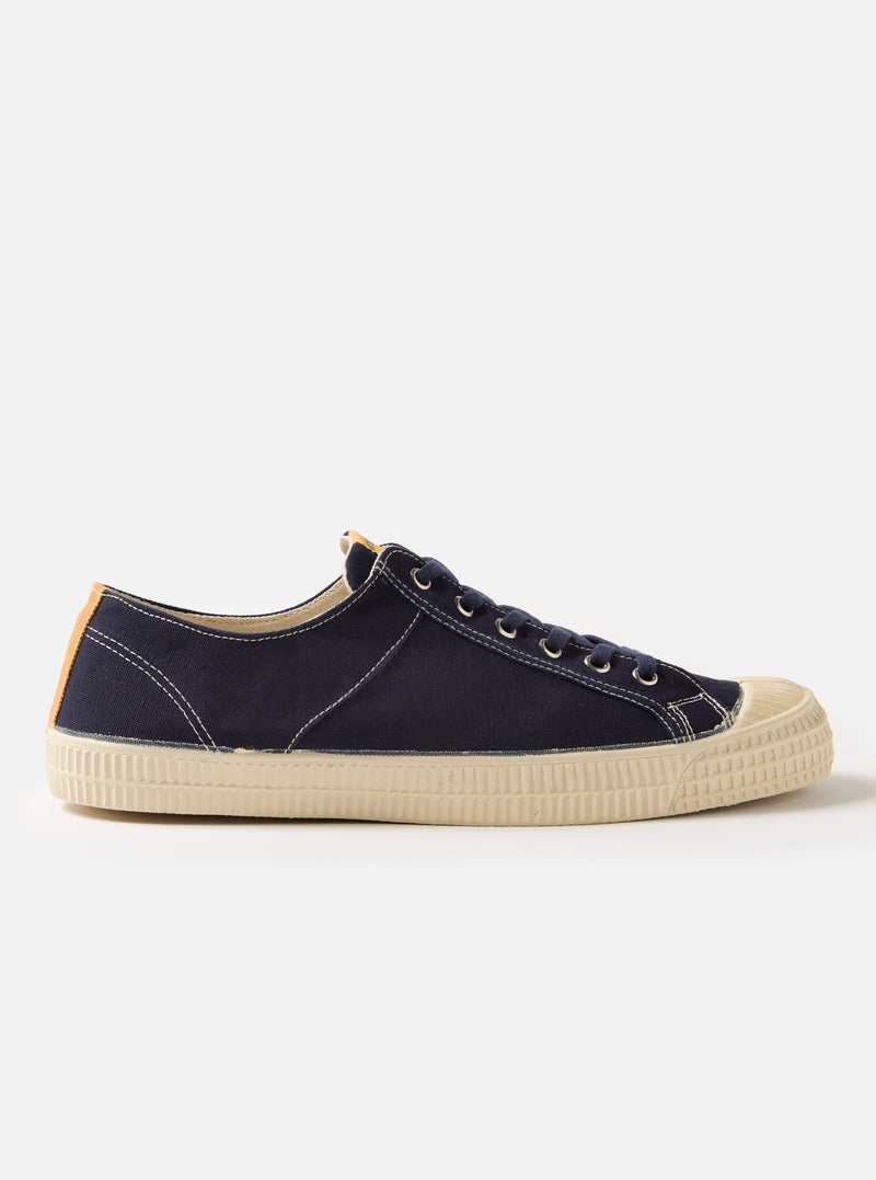 Side view of the Novesta for Universal Works Navy Canvas Star Master shoe on a white background. The shoe is navy canvas with a cream rubber sole.