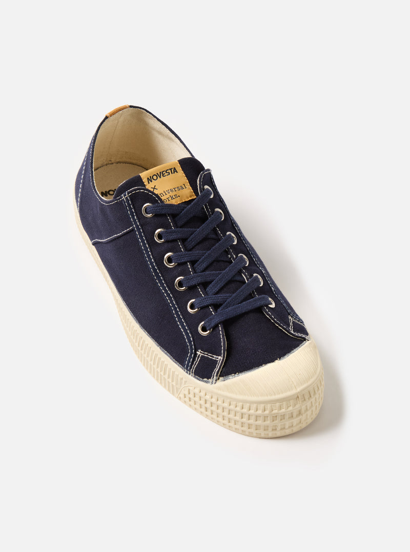 Studio shot of a Novesta for Universal Works Navy Canvas Star Master shoe. The navy canvas upper contrasts with the off-white rubber sole. Set against a plain white background.