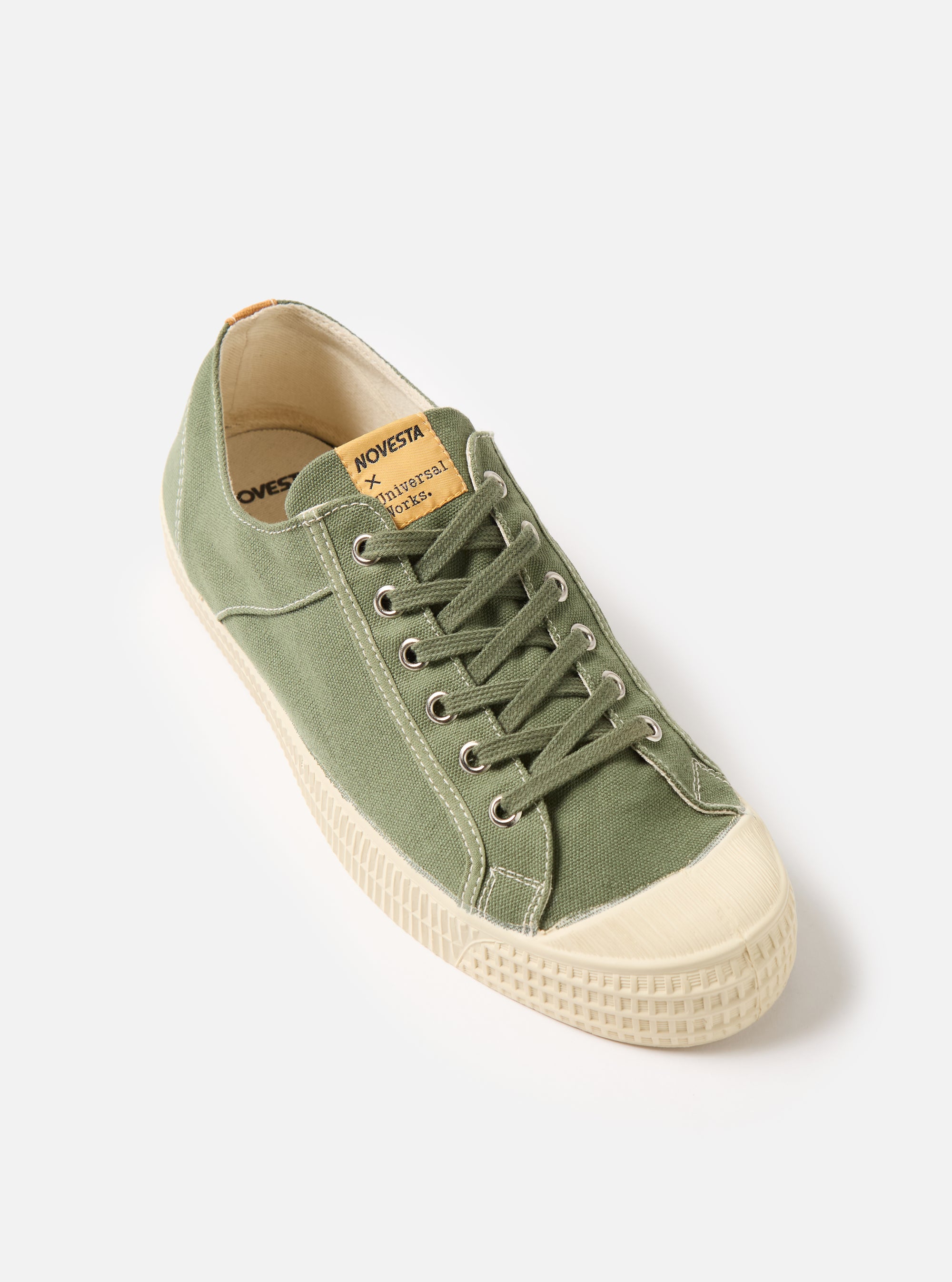 The Novesta for Universal Works Olive Canvas Star Master shoe on a white background. The shoe is olive green canvas with a cream rubber sole and toe cap.