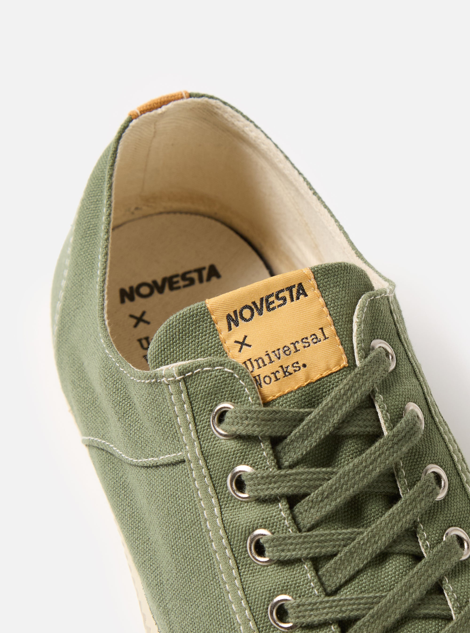 Close-up of the Novesta for Universal Works Olive Canvas Star Master shoe. The olive canvas and laces are detailed, with a white background emphasizing the shoe's design.