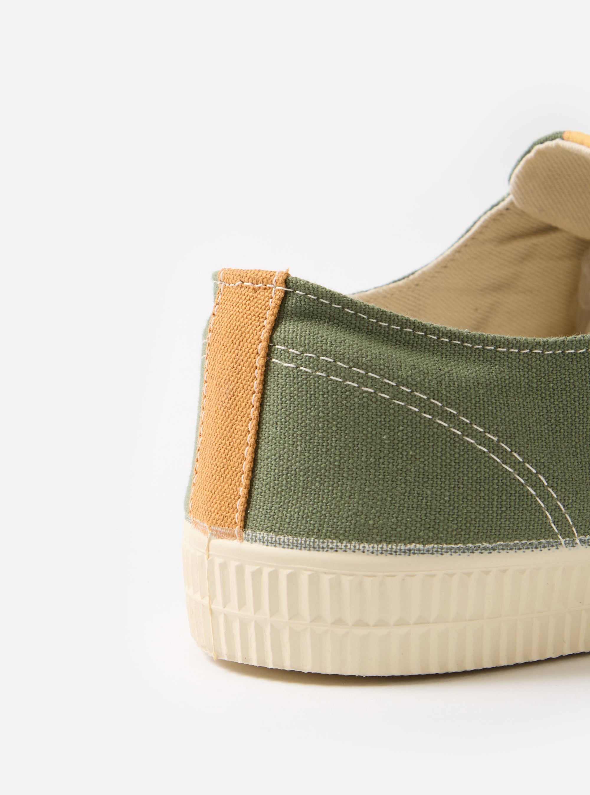 Close-up of the Novesta for Universal Works Olive Canvas Star Master shoe. Features olive canvas, tan heel detail, and a textured white sole. Shot on a clean white background.