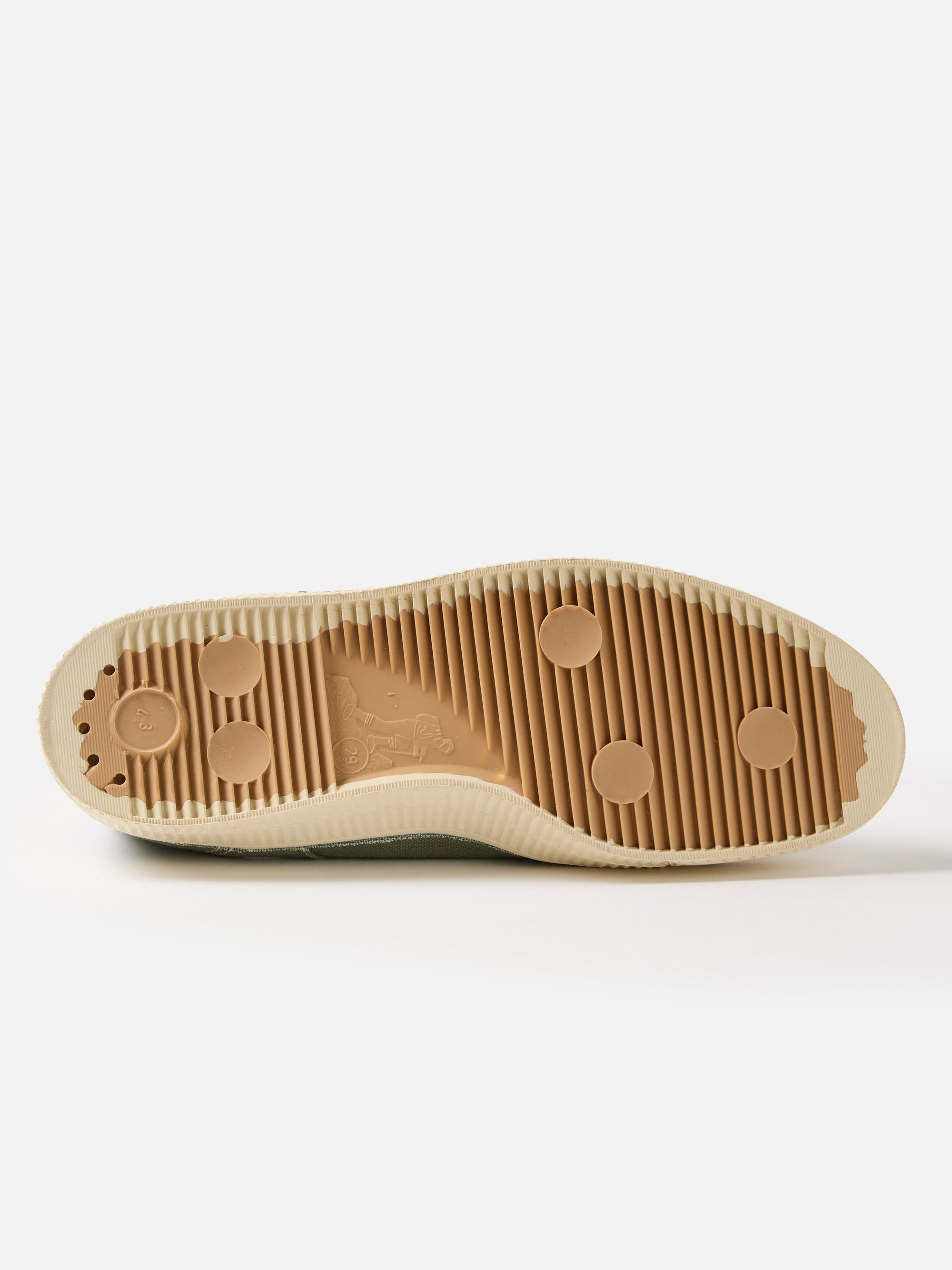 Close-up of the sole of a Novesta for Universal Works Olive Canvas Star Master shoe. The sole is tan with a ribbed pattern and circular details. The shoe is on a white background.