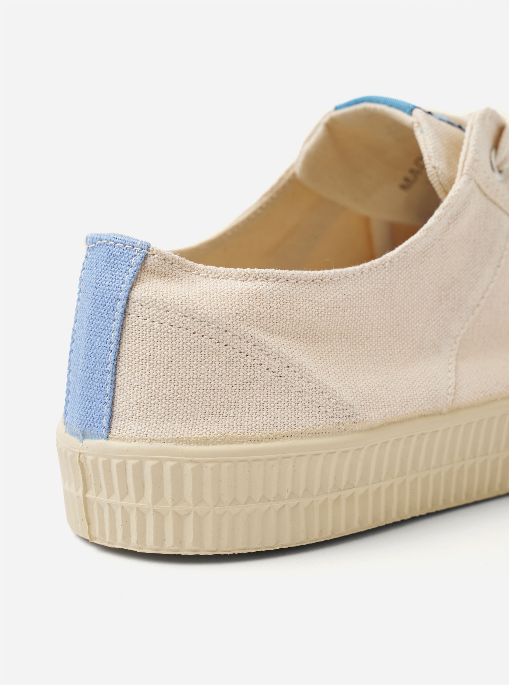 The Novesta for Universal Works Ecru/Pale Blue Canvas Star Master is shown from a side profile view against a white background. The low-top sneaker features an ecru cotton canvas upper with tonal stitching and silver-tone metallic eyelets. A distinctive pale blue heel strip provides a point of contrast, and the thick, textured natural rubber sole is ecru in color.