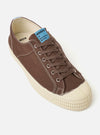 The Novesta for Universal Works Brown/Pale Blue Canvas Star Master is shown against a white background. The sneaker features a dark brown cotton canvas upper with a contrasting pale blue heel tab and a chunky ecru vulcanized rubber sole. The design includes tonal brown laces, metallic eyelets, and the signature textured rubber toe cap and foxing.