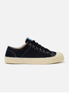 The Novesta for Universal Works Black/Pale Blue Canvas Star Master is shown from a side profile as a flat lay against a white background. The low-top sneaker features a black cotton canvas upper with contrast white stitching and metallic eyelets. A signature chunky ecru vulcanized rubber sole and toe cap are prominent, with a pale blue flash detail on the heel.