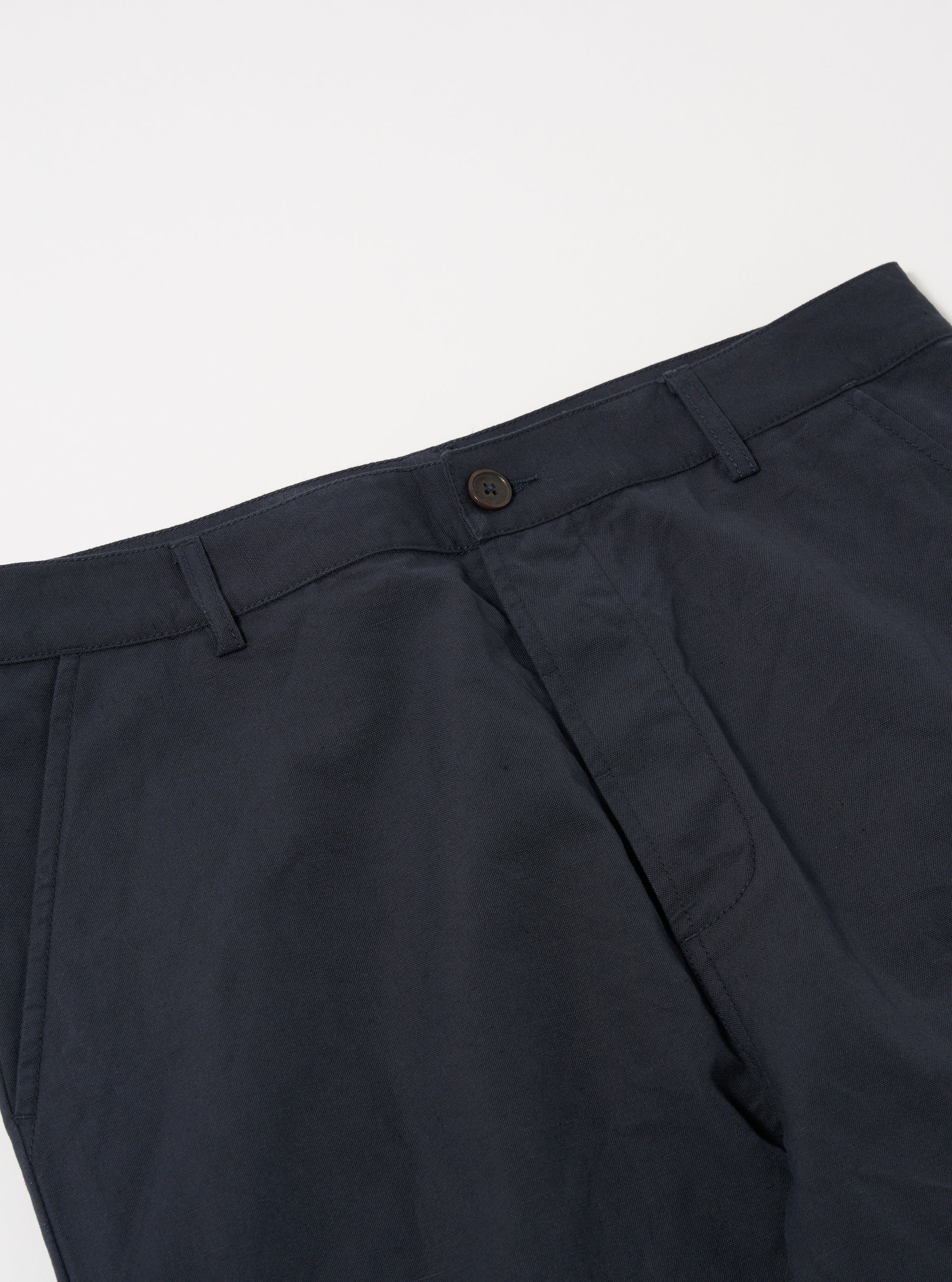 Close-up of the Navy Linen Slub Weave Military Chino on a white surface. The navy linen fabric and button are clearly visible.