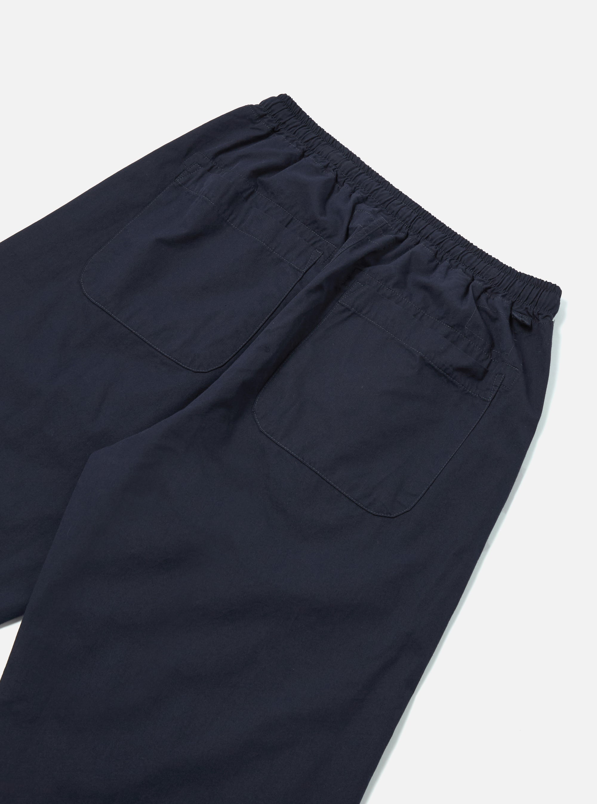 Close-up of the back of navy cotton Judo Pant on a white surface. The pants have an elastic waistband and two back pockets.