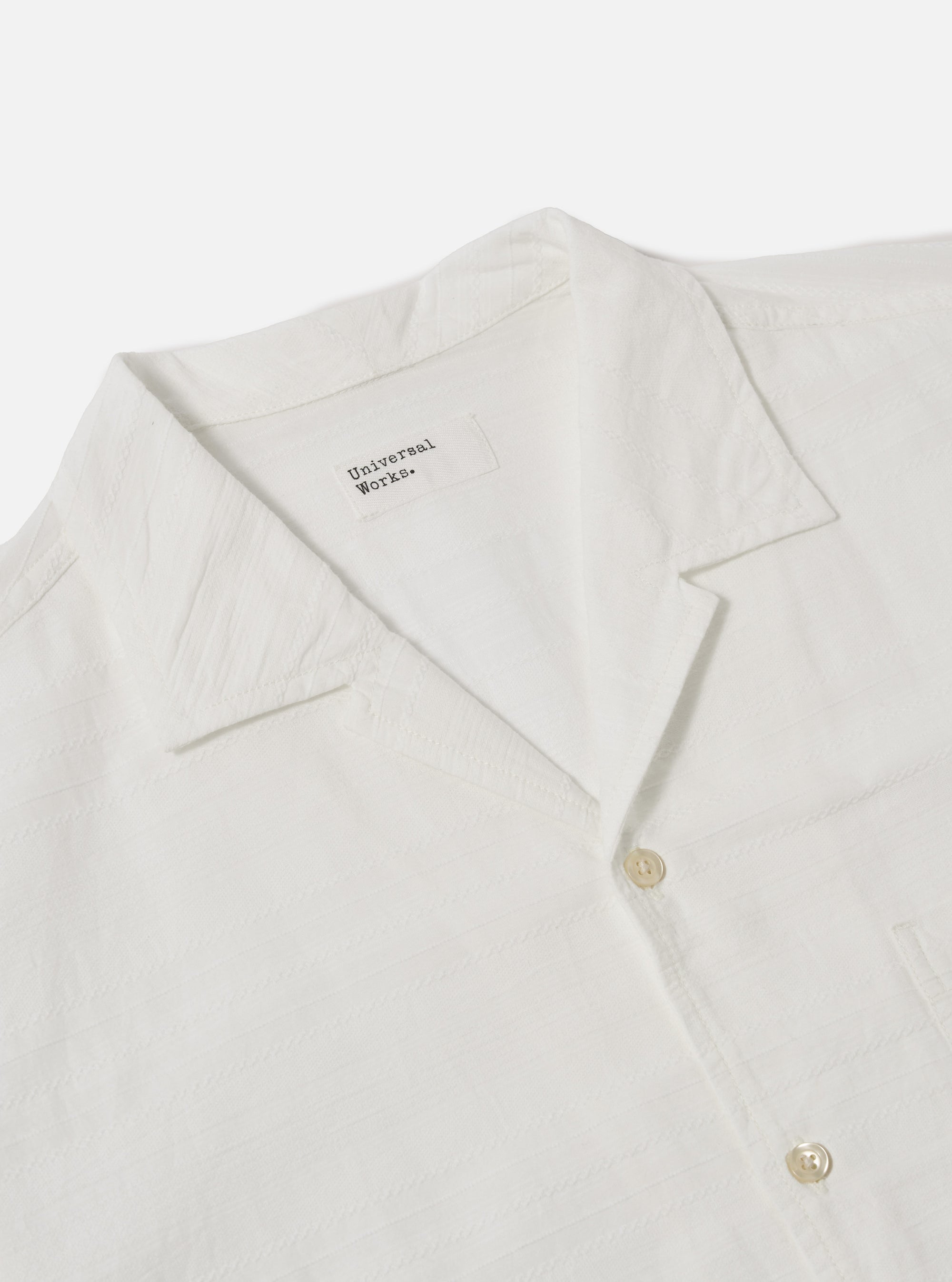 Close-up of the Ecru Deffe Self Stripe Minari Shirt on a white background. The shirt is ecru-colored with a self-stripe pattern. Features a camp collar and button closure.