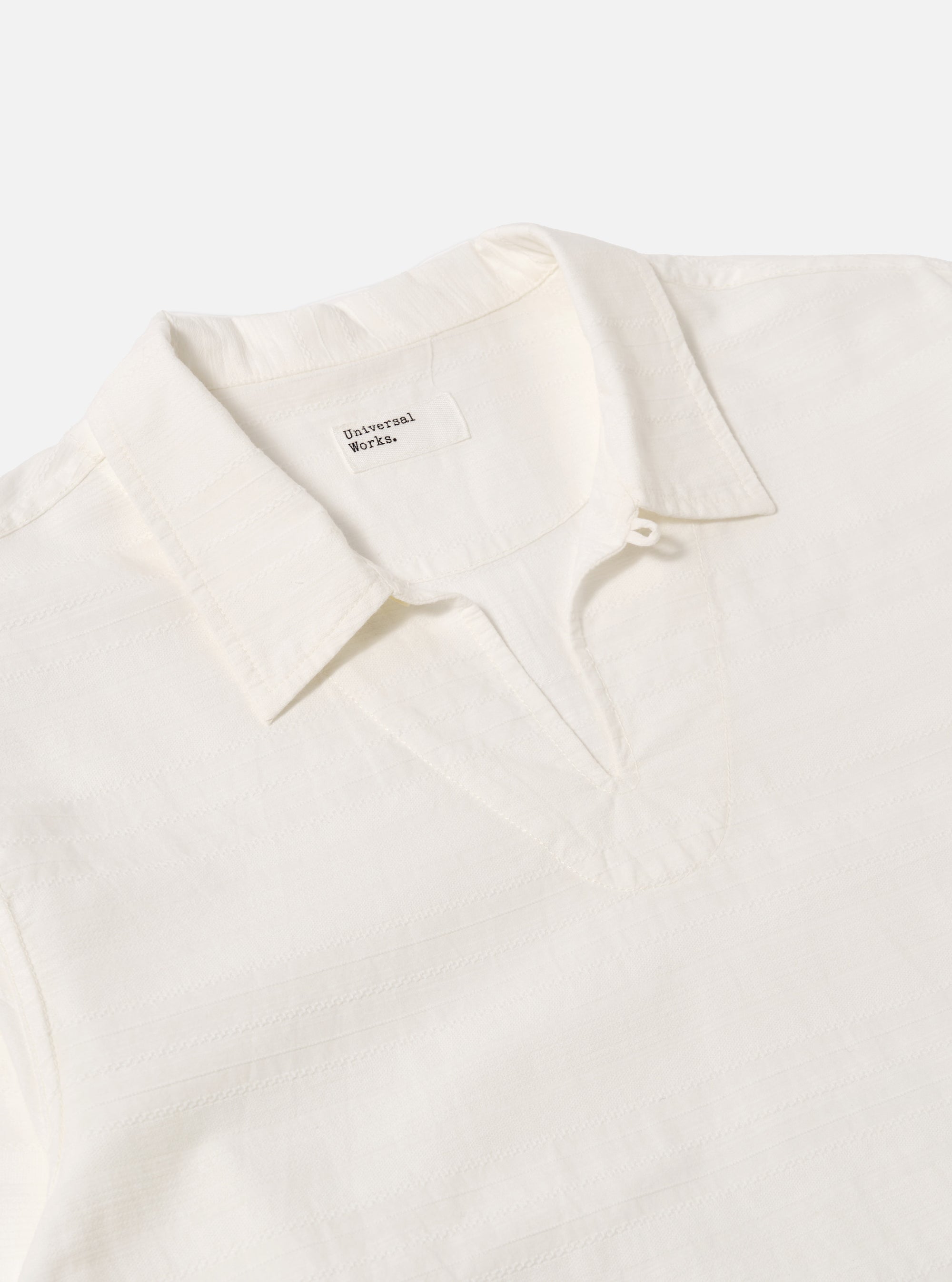 Close-up of the Ecru Deffe Self Stripe Smock Overshirt on a white background. The shirt is a light cream color with subtle stripes. The collar is open and the fabric is textured.