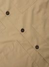 Close-up of the Sand Military Cotton Dockside Overshirt. The sand-colored cotton fabric features brown buttons and detailed stitching. Shot on a flat, neutral surface.