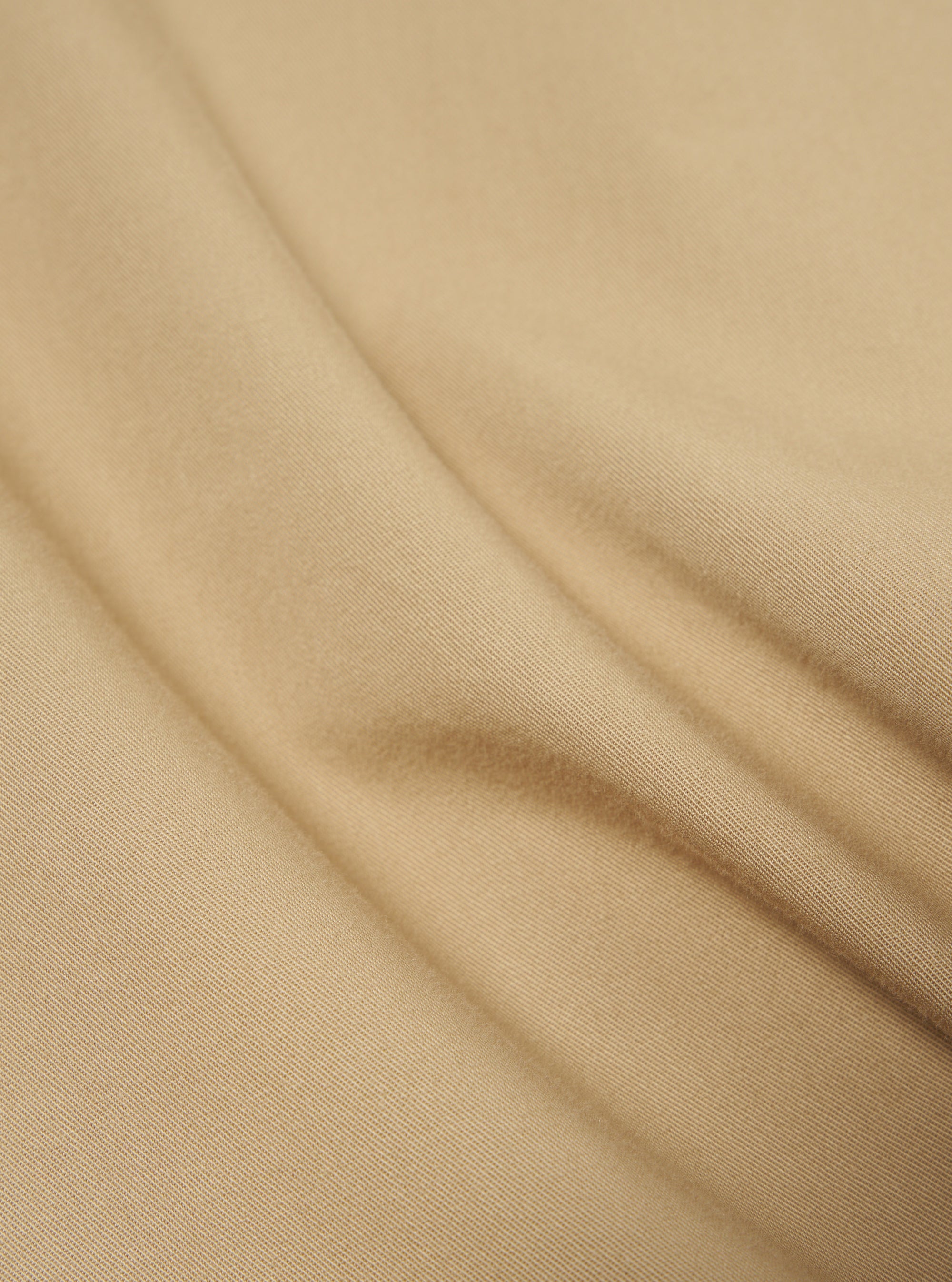 Close-up of the sand-colored cotton fabric of the Military Cotton Dockside Overshirt, showing the texture and weave of the material.