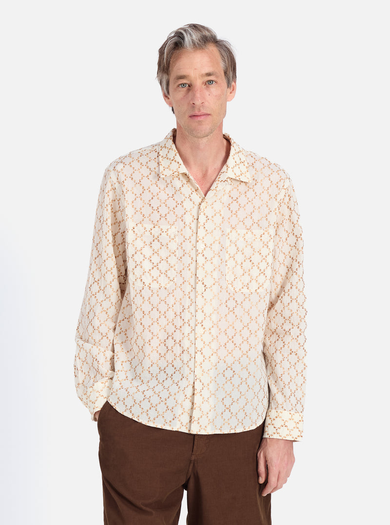 A man models the Camel Mitla Weave Work Shirt, cream with a brown woven pattern. He wears brown pants. Shot on a white background.