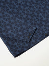 Close-up of the Navy Mitla Print Cord Liam Jacket on a white surface. The jacket features a navy geometric print and corduroy texture. Sleeve detail with button closure.