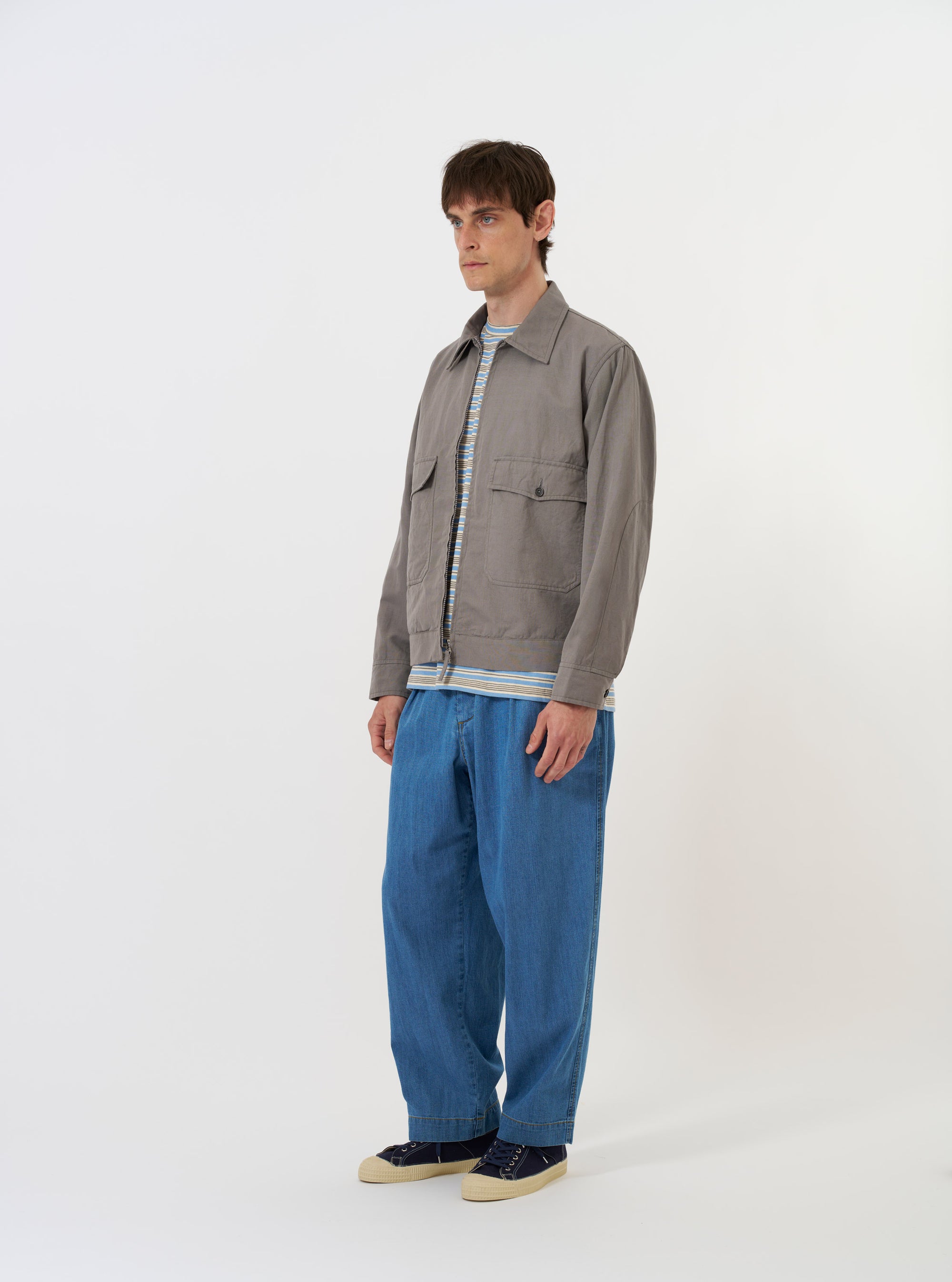 The Mid Grey Linen Slub Weave E130 Jacket is shown laid flat against a plain white background. The jacket features a full button front, a classic collar, and two large patch pockets at the hips. The mid-grey fabric has a visible slubbed texture.