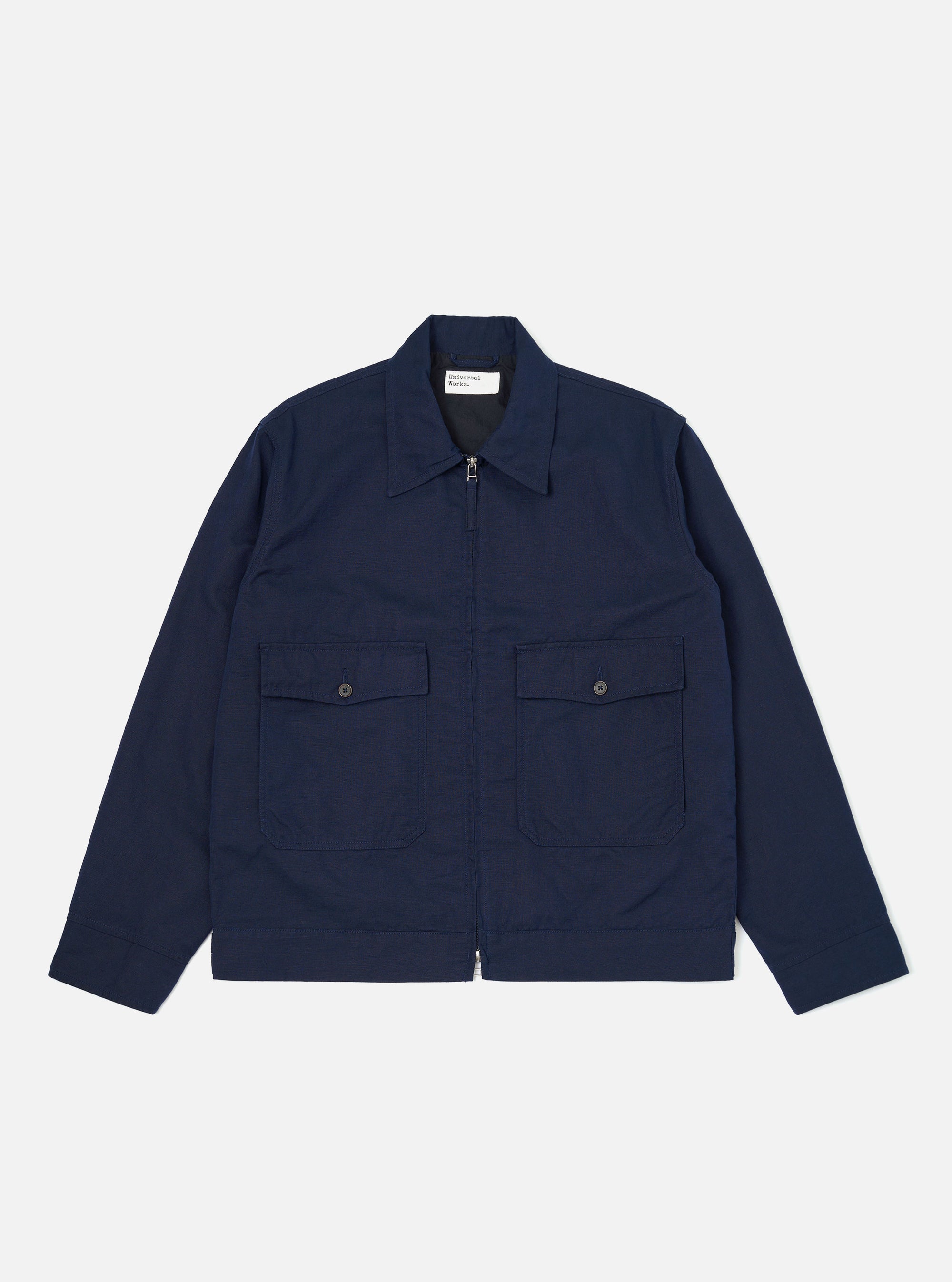 The Navy Linen Slub Weave E130 Jacket is shown laid flat against a solid white background. The jacket features a classic collar, a full-button front, and two large patch pockets at the waist. The textured slub weave of the navy linen-cotton fabric is visible throughout the garment.