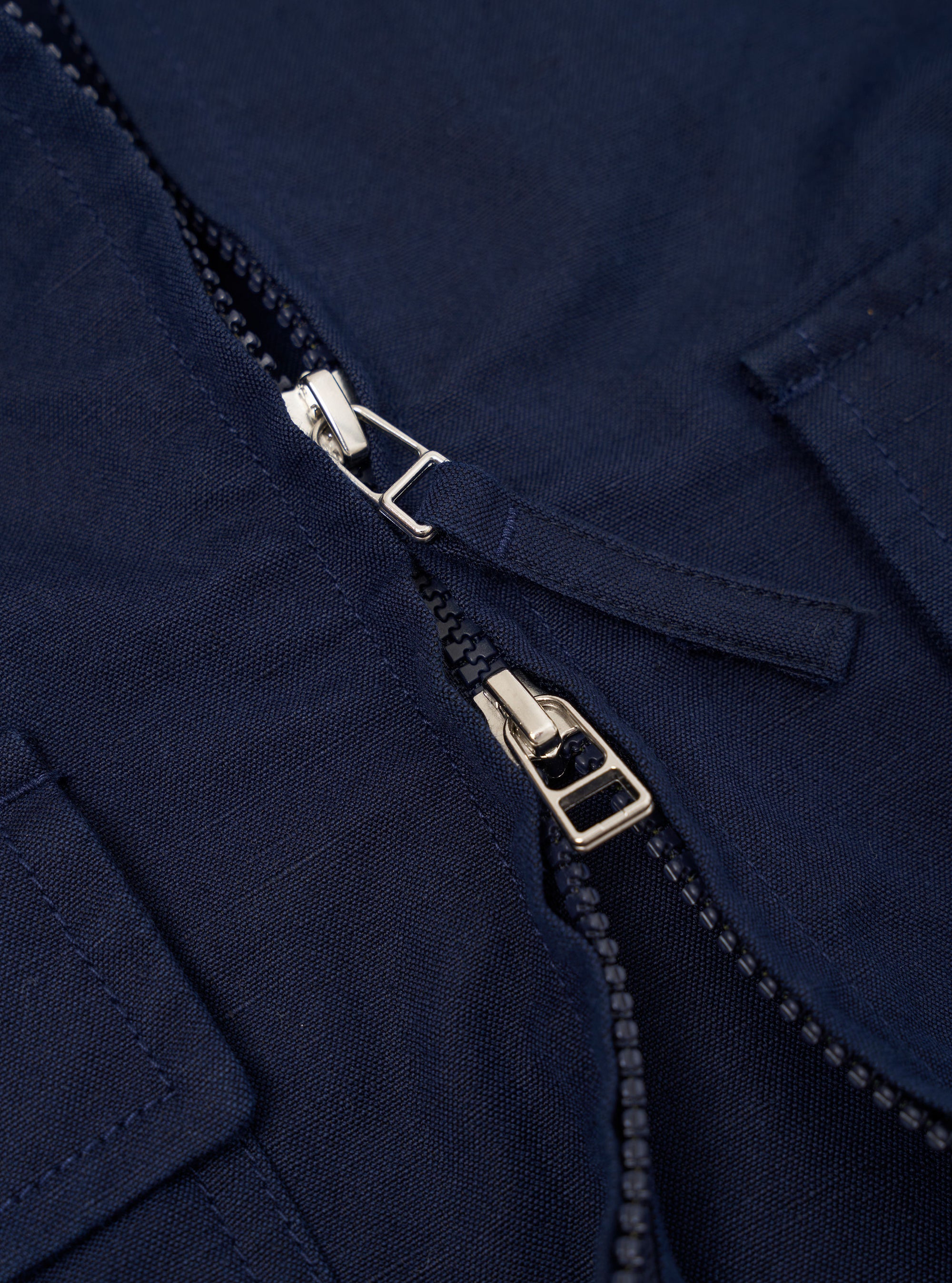 The Navy Linen Slub Weave E130 Jacket is shown from the back, laid flat against a plain white background. The image highlights the garment's simple, clean construction, featuring a straight hem and a classic collar.