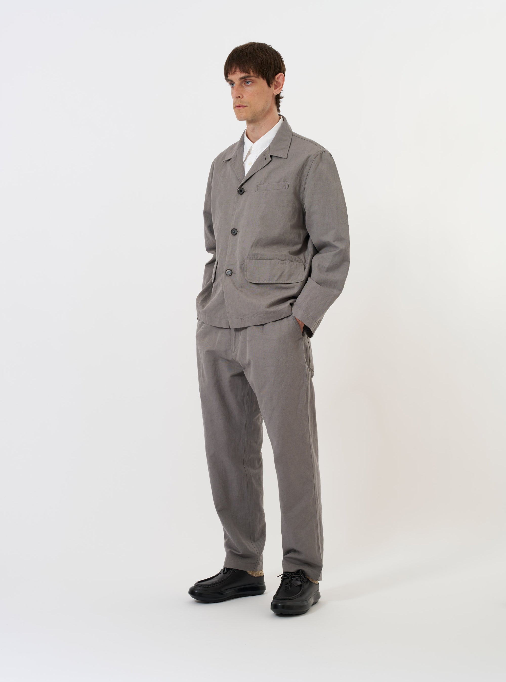 The Mid Grey Linen Slub Weave Franck Jacket is shown laid flat against a solid white background. The garment features a textured slub weave, a three-button front closure, a classic lapel, and two large patch pockets at the hips with a smaller patch pocket on the chest.