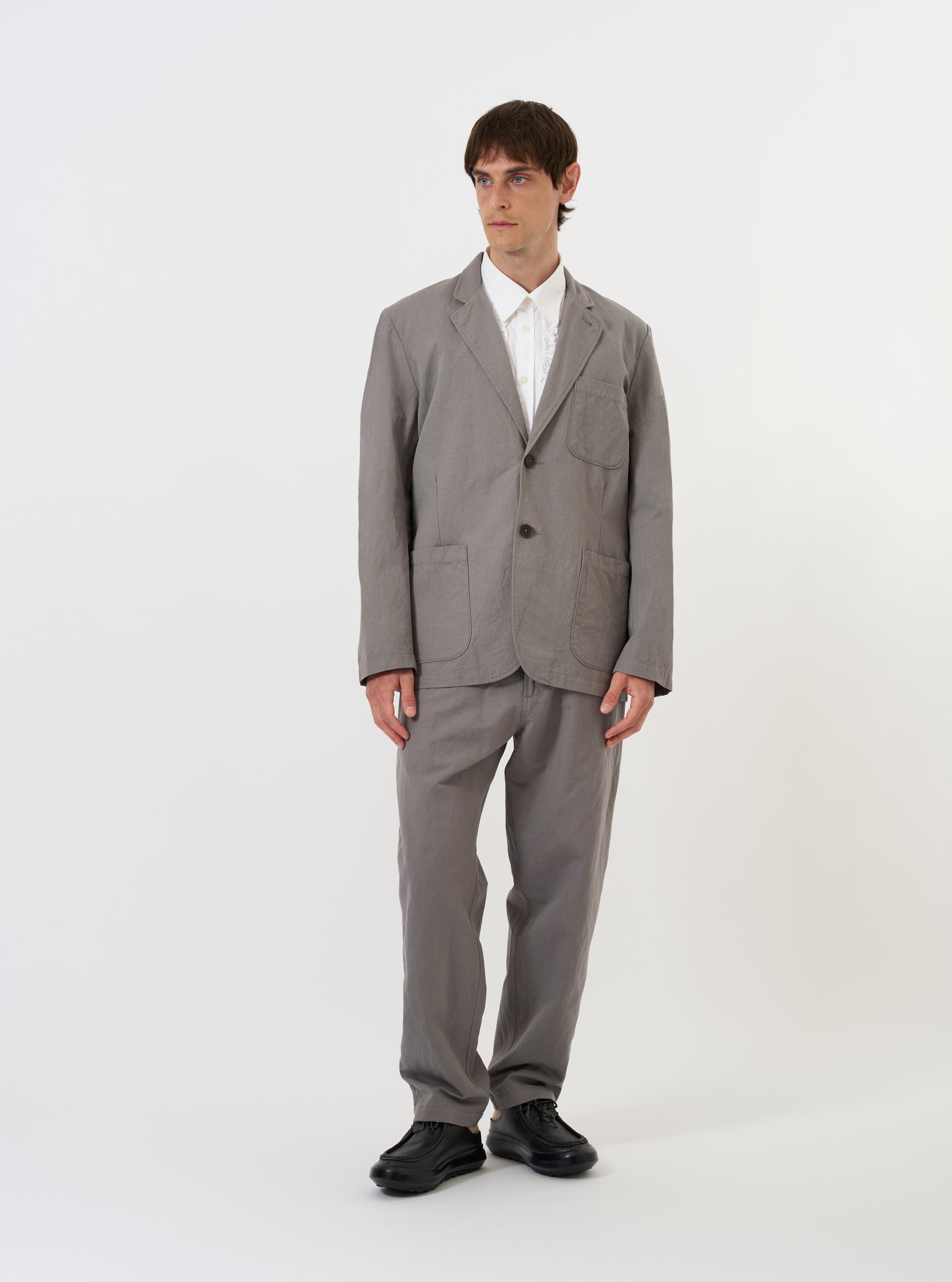 The Mid Grey Linen Slub Weave Two Button Jacket is shown laid flat against a plain white background. The image highlights the jacket's textured slub weave, two-button front, wide lapels, and three front patch pockets.