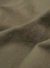 A close-up fabric swatch of the Olive Linen Slub Weave Two Button Jacket highlights the textured olive green material. The image showcases the distinct slubby appearance of the weave, characterized by visible horizontal and vertical threads.