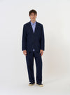 A Navy Linen Slub Weave Two Button Jacket is shown laid flat against a plain white background. The jacket features a classic notch lapel, a two-button front fastening, and three patch pockets on the front. The textured slub weave of the navy blue linen-cotton fabric is visible.
