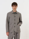 The Mid Grey Linen Slub Weave Bakers Jacket is shown laid flat against a plain white background. This chore-style jacket features a classic pointed collar, a five-button front, and four front patch pockets: one asymmetrical chest pocket and three lower pockets. The mid-grey fabric has a visible slub texture.