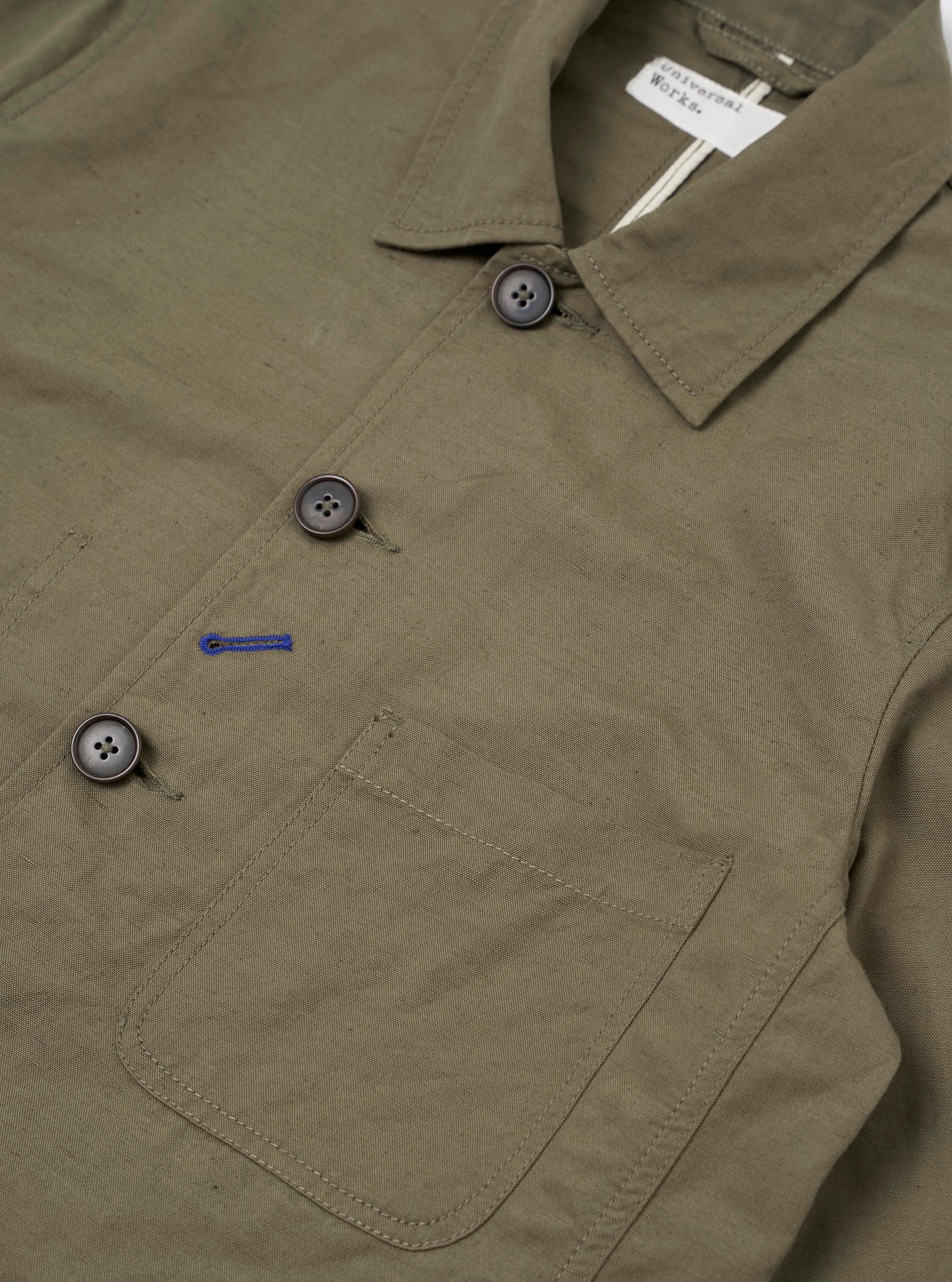 The Olive Linen Slub Weave Bakers Jacket is shown from the back as a flat lay against a plain white background. The image highlights the textured olive green linen-cotton blend fabric and the clean, straight-cut construction of the jacket's rear panel.