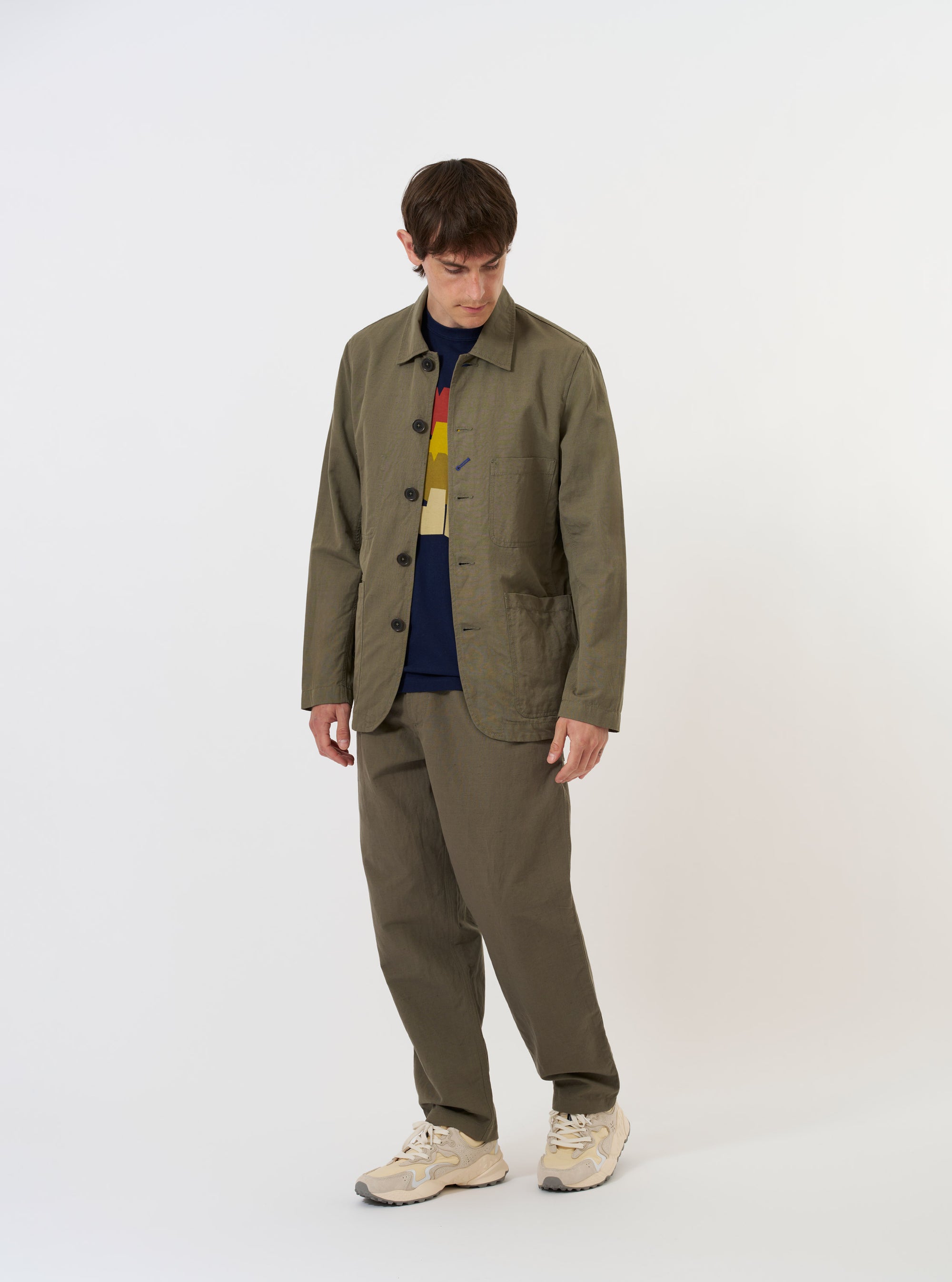 An Olive Linen Slub Weave Bakers Jacket is shown laid flat against a solid white background. The jacket features a classic pointed collar, a five-button front, and four prominent patch pockets on the front. The olive green linen fabric has a visible textured slub weave throughout.