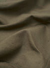 A close-up fabric swatch of the Olive Linen Slub Weave Bakers Jacket displays the detailed texture and irregular weave of the olive green linen-blend material. The fabric is shown as a flat, square sample with no model or mannequin present.