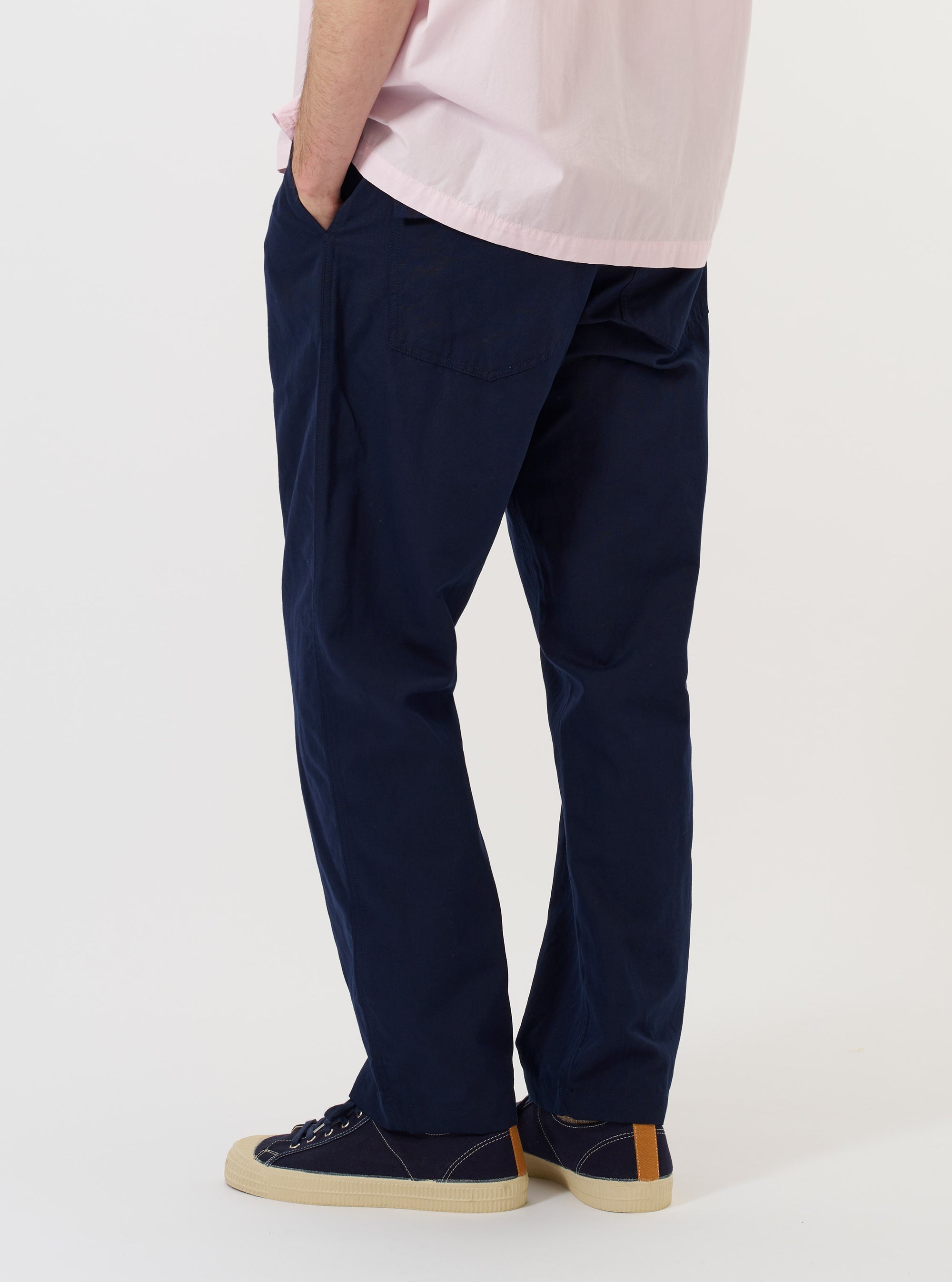 A model is wearing the Navy Linen Slub Weave Dizzy Trouser against a plain white background. The image shows the trousers from the waist down, highlighting the loose, wide-leg fit and the textured slub weave of the navy linen fabric. One hand is partially visible in a side pocket.