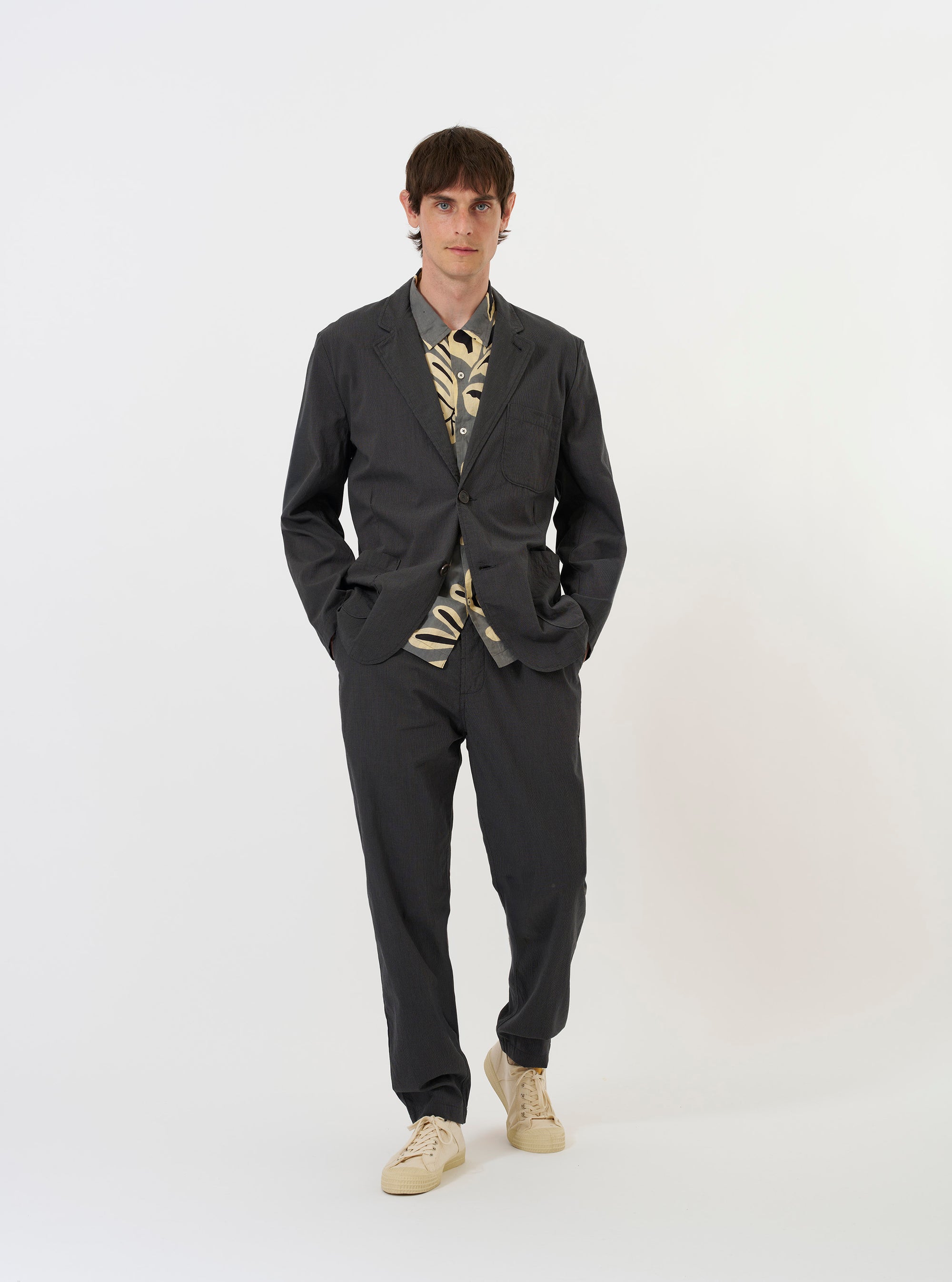 The Charcoal Seattle Cotton Two Button Jacket is shown laid flat against a solid white background. The jacket features a classic two-button front fastening, a notched lapel, two large patch pockets at the hips, and a single chest patch pocket. The charcoal grey cotton fabric has a visible fine texture.