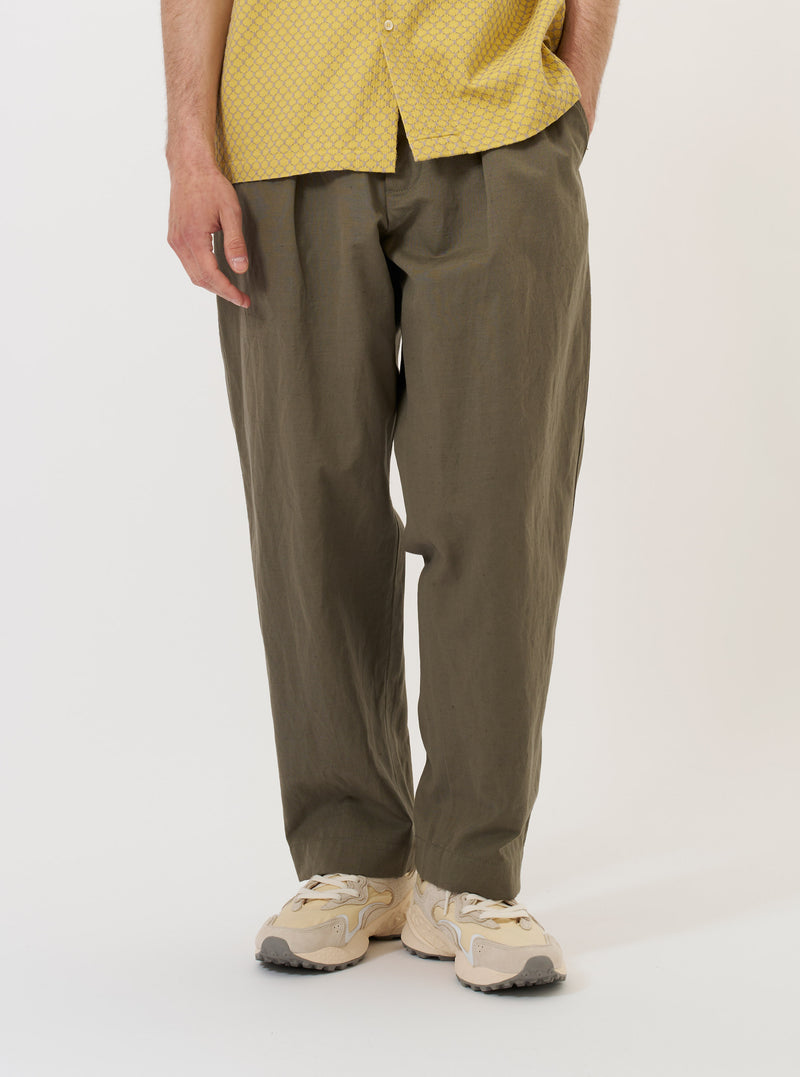 The Olive Linen Slub Weave Oxford Pant is shown laid flat against a plain white background. The trousers feature a wide loose leg, a single pleat front, and an elasticated waistband with a visible drawstring. Two side pockets and a button fly are prominent.