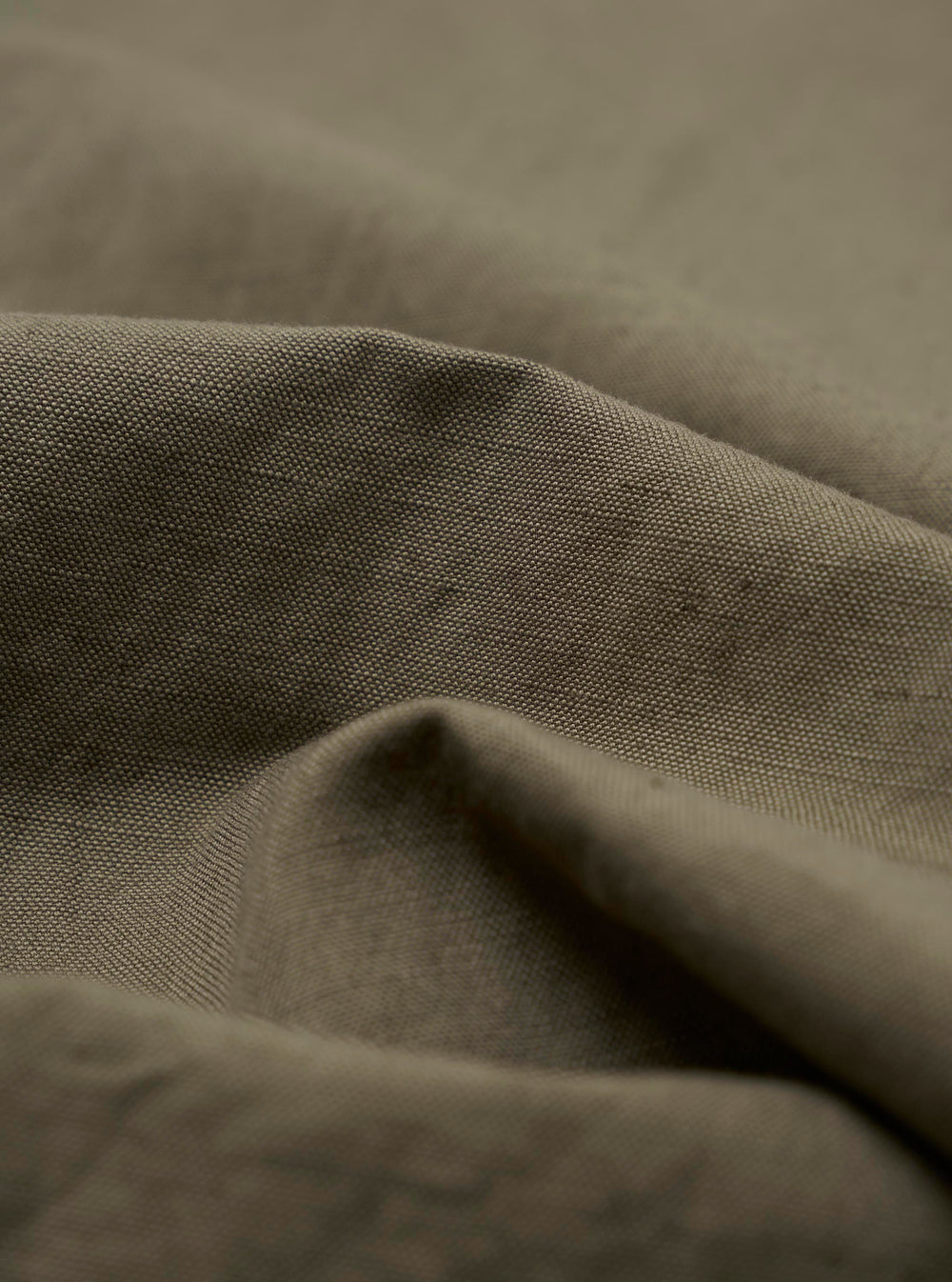 A detailed close-up fabric swatch of the Olive Linen Slub Weave Oxford Pant, highlighting the olive green color and the distinct, textured slub weave of the fabric. The material is shown against a neutral background.