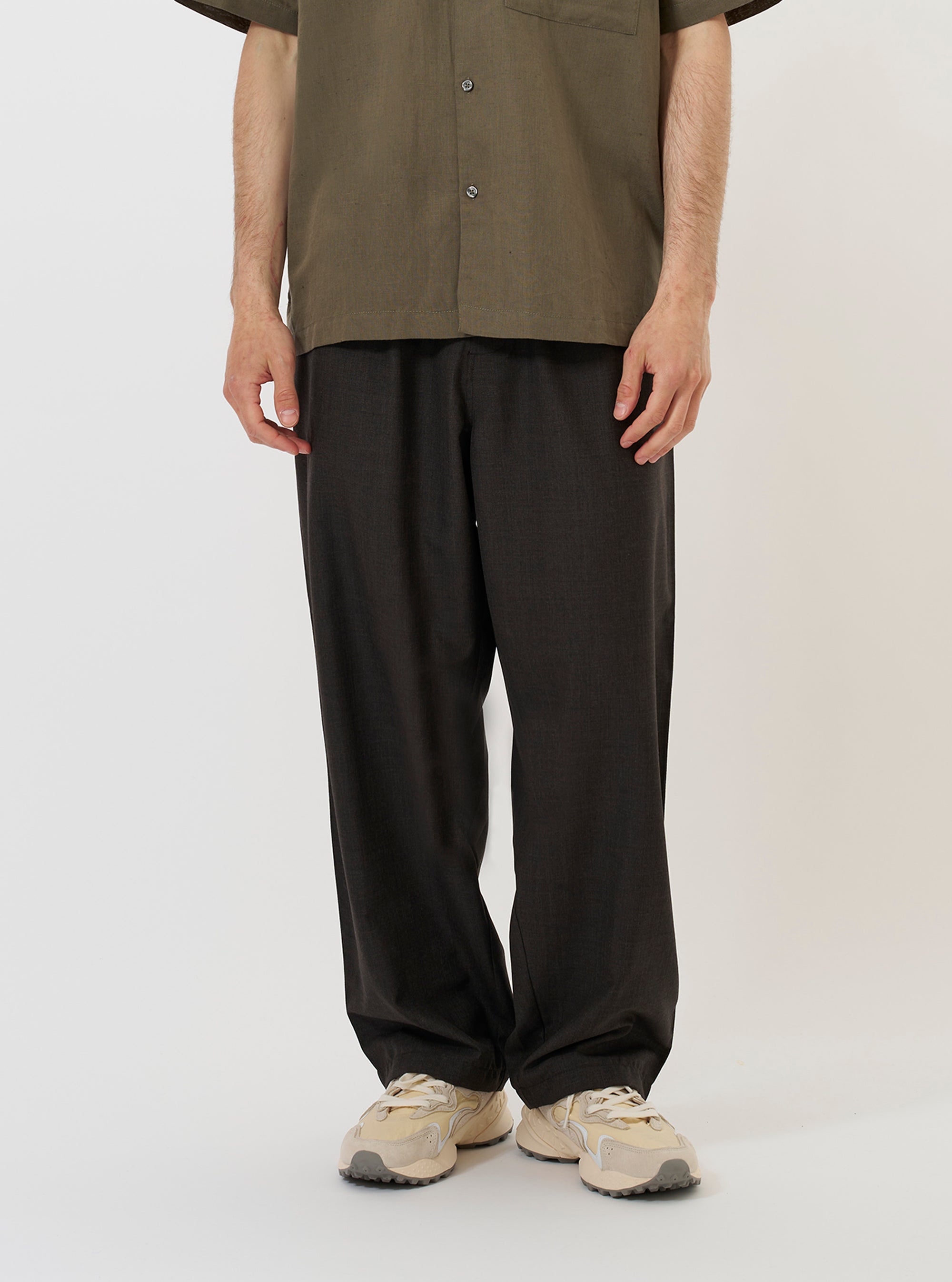 A model is wearing the Brown Marl Tropical Suiting Dutch Pant against a plain white background. The trousers are shown from the waist down, highlighting the loose, wide-leg silhouette and the distinct stitched-down front darts that add volume to the design. The garment is made from a heathered brown marl fabric.