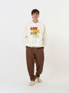 The Ecru Brush Back Sweat FM Raglan Sweatshirt is shown laid flat against a plain white background. The garment is an ecru-colored long-sleeve sweatshirt featuring raglan sleeves, a classic crew neck with a ribbed V-insert, and ribbed cuffs and hem.