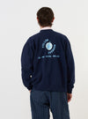 A model is wearing the Navy Brush Back Sweat FM Raglan Sweatshirt against a plain white background. The image, taken from a rear-side perspective, highlights the raglan sleeve construction and the ribbed texture of the cuffs and hem.