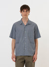 A pale blue check plaid summer overshirt is displayed flat against a plain white background. The garment features a standard pointed collar, a full button-down front, and two prominent utility chest pockets with buttoned flaps. The fabric has a light blue and white plaid pattern.