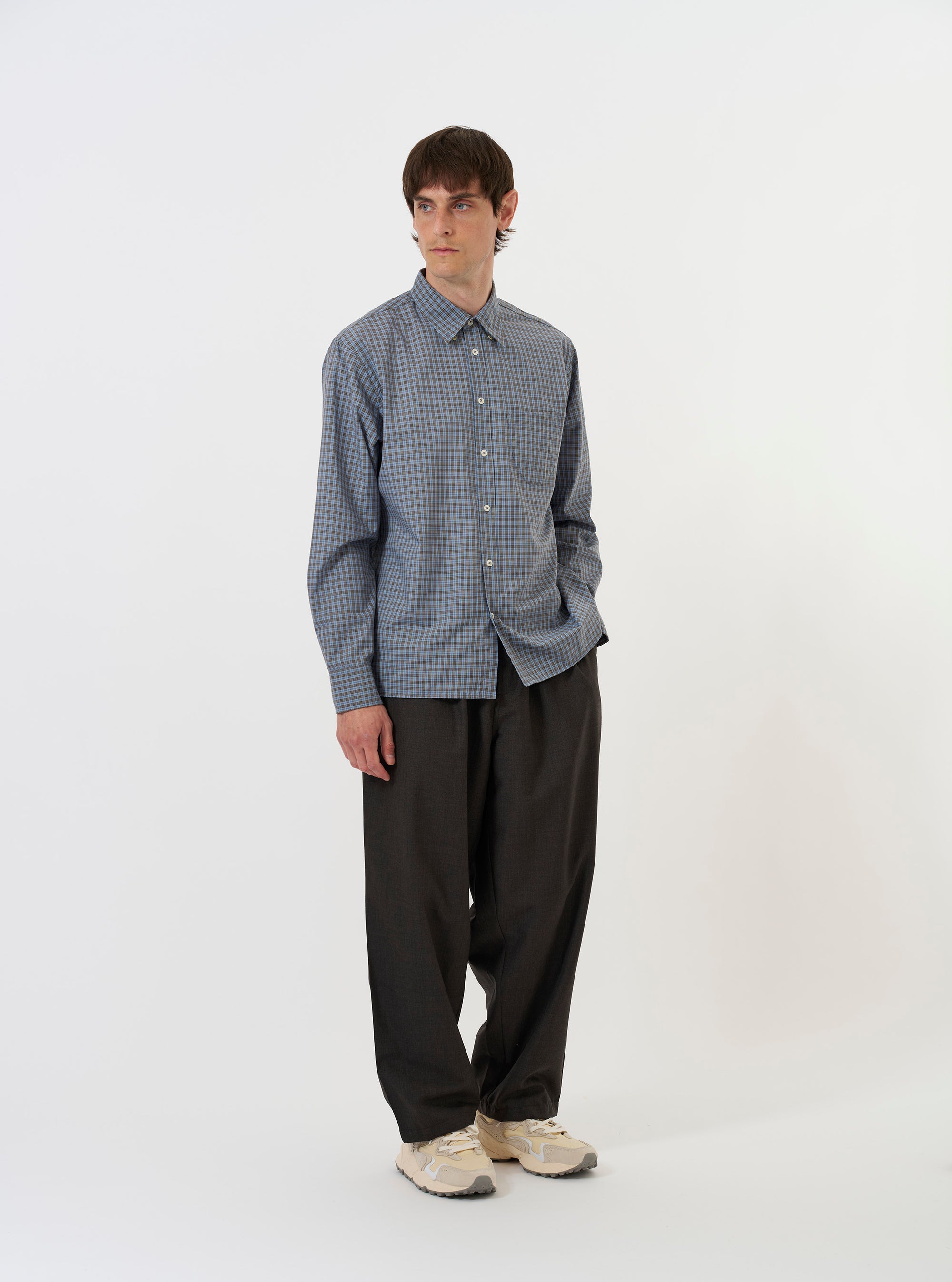 The Pale Blue Check Plaid Lazy Day Shirt is shown laid flat against a plain white background. The shirt is a long-sleeve button-down with a pointed collar, a single asymmetric chest pocket on the left side, and a straight hem. The fabric features a small-scale pale blue and white check pattern.