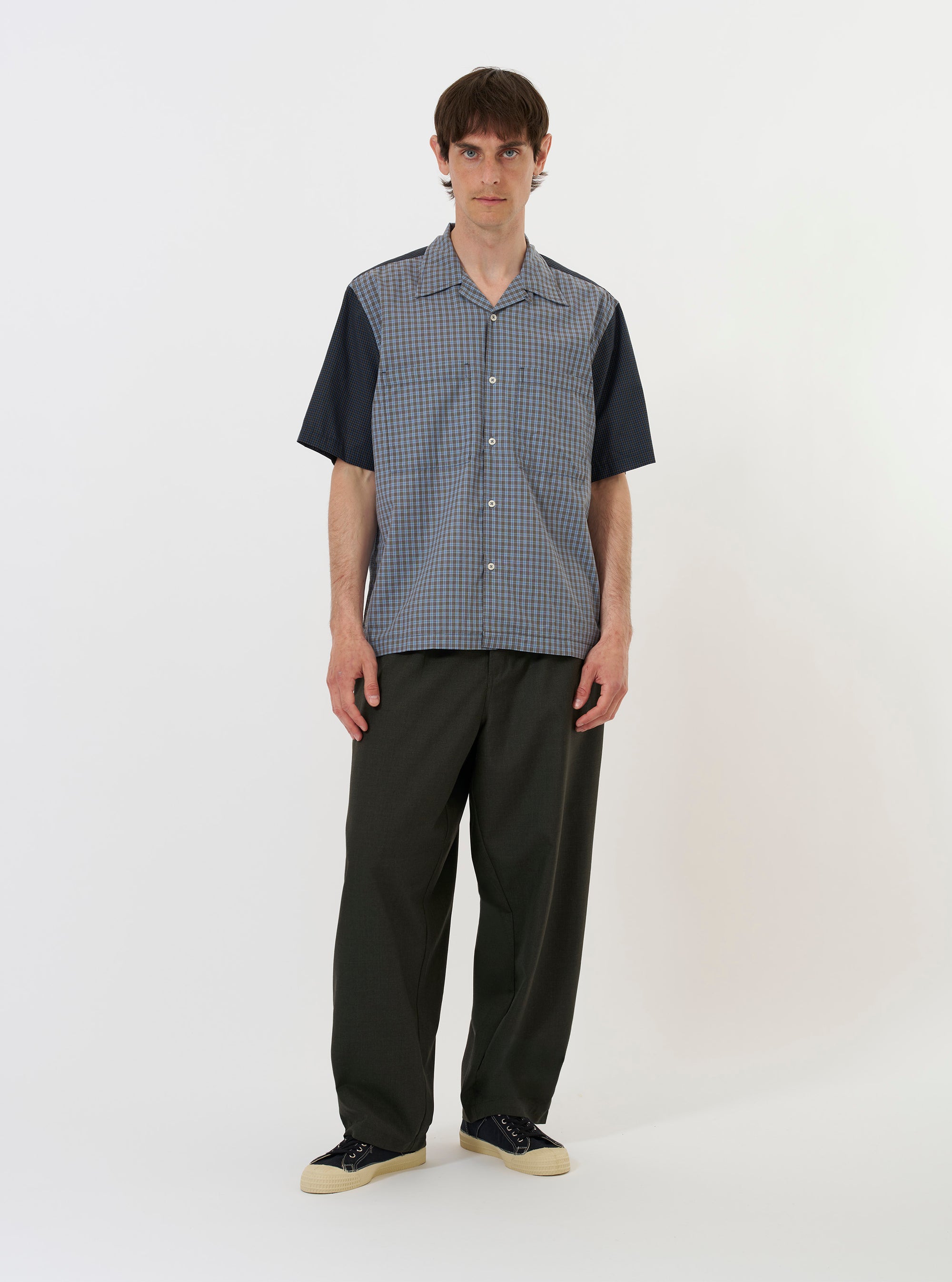 A Mixed Check Plaid Camper Shirt is laid flat against a plain white background. The shirt features a patchwork design of various blue, white, and red plaid patterns, a camp collar, a button-down front, and a single chest pocket.