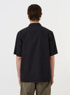 The Black Broadcloth Camp Shirt is shown from the back, displayed flat against a plain white background. The image highlights the horizontal back yoke with two small pleats for added volume and the straight hem with side splits.